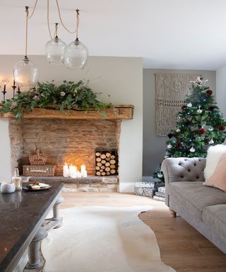 Wooden mantelpiece with brick hearth beyond open fire and decorated Christmas tree