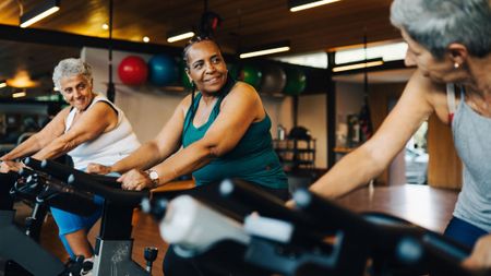 A group of women riding on exercise bikes in the gym