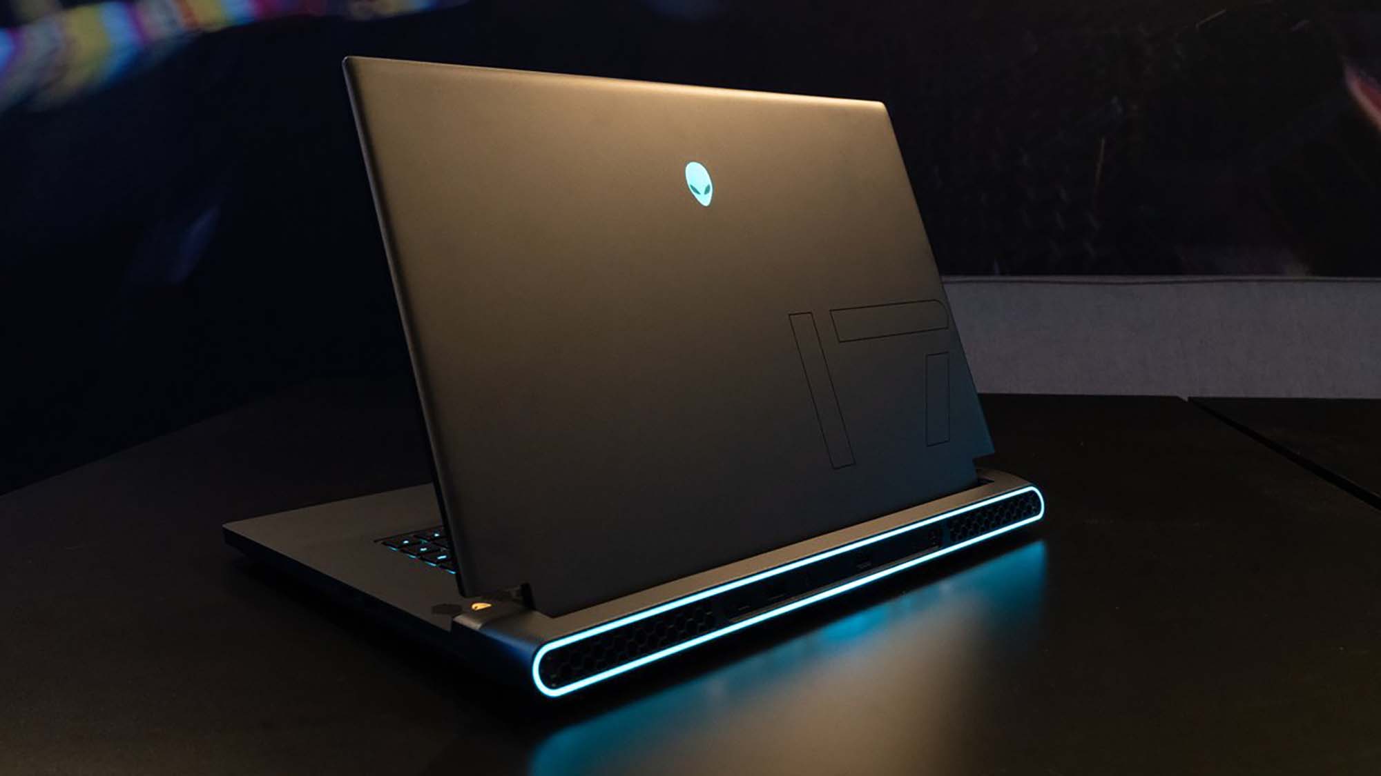 An Alienware gaming laptop sitting on a table in a darkened room