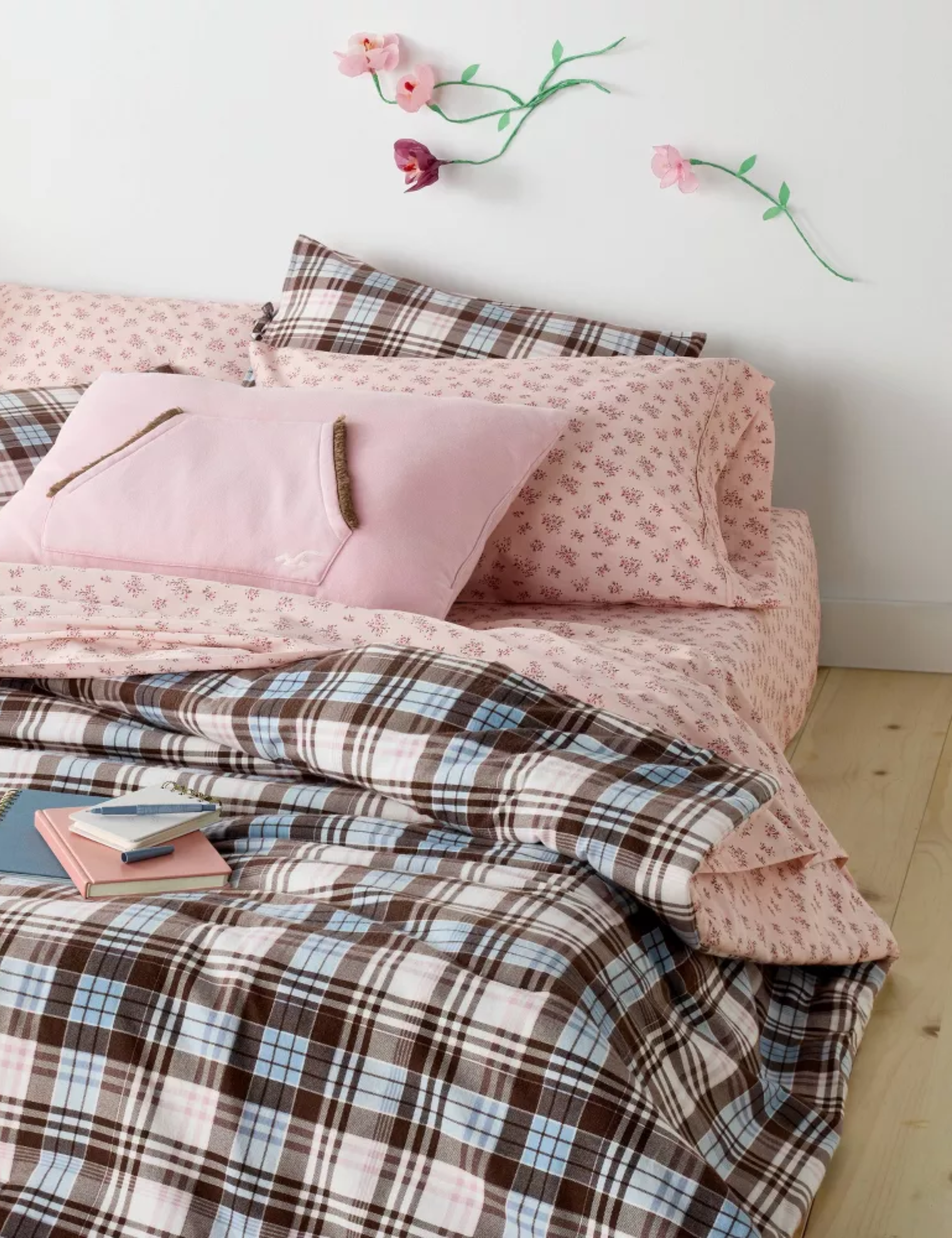 Eclectic plaid-and-floral dorm room bedscape styled with the new Hollister x Target Studdy Buddy Pillow