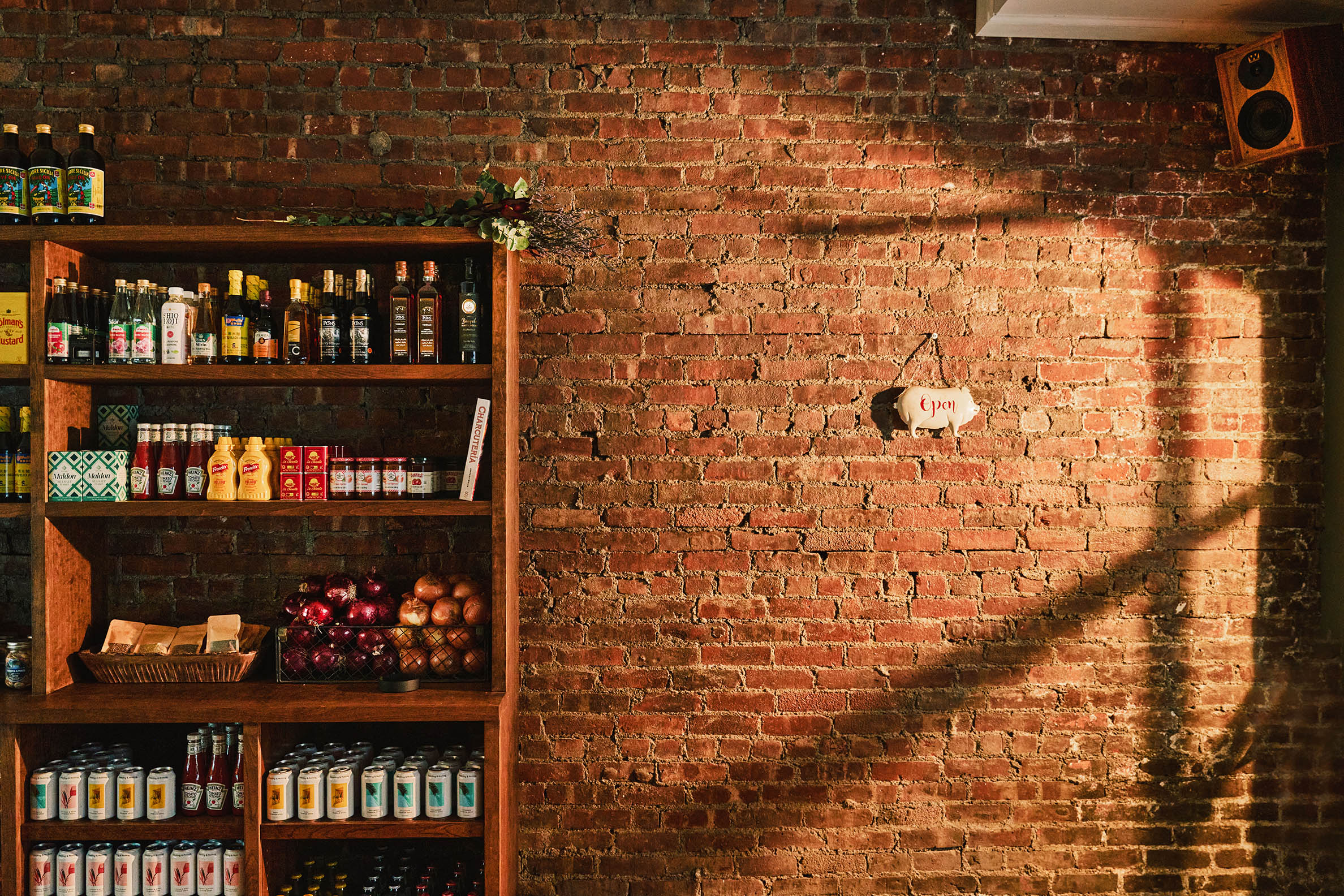 Interior shots of a brick, wood, and marble-clad cafe, bakery, and butcher, decorated with modern rustix furnishings and floral wallpaper.