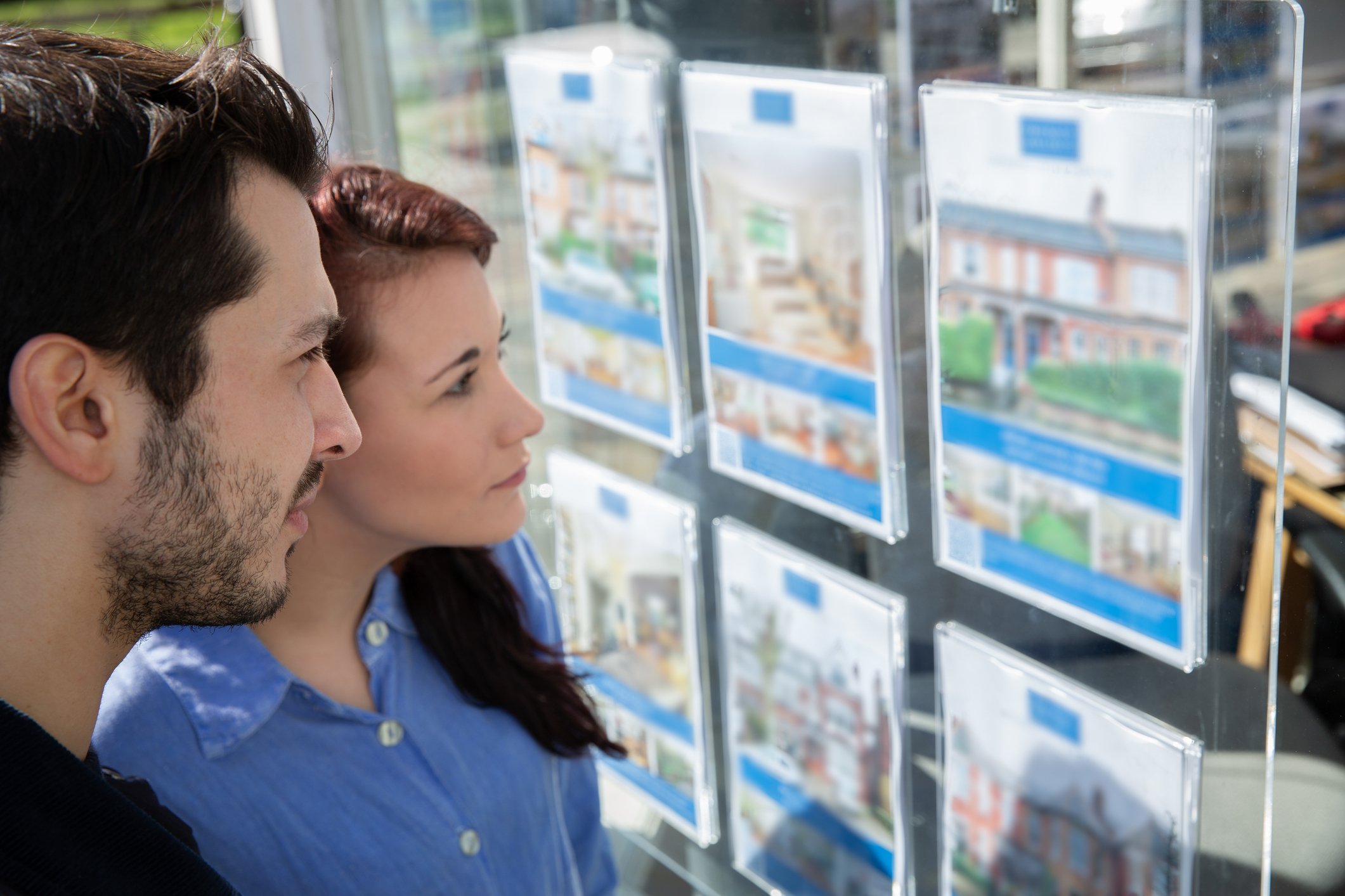 Couple looking at houses for sale in estate agent window