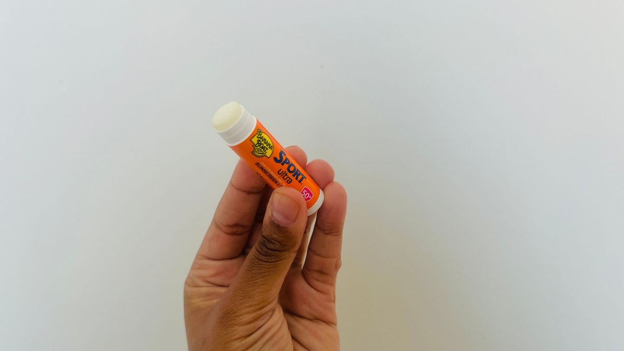 A person holding an opened Banana Boat Sport SPF lip balm.