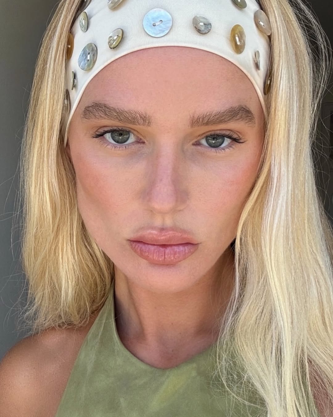 Megan Adelaide with bronzed, glowy skin and a button-detailed headband