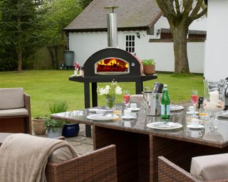 A log fired pizza oven and outdoor table on a patio