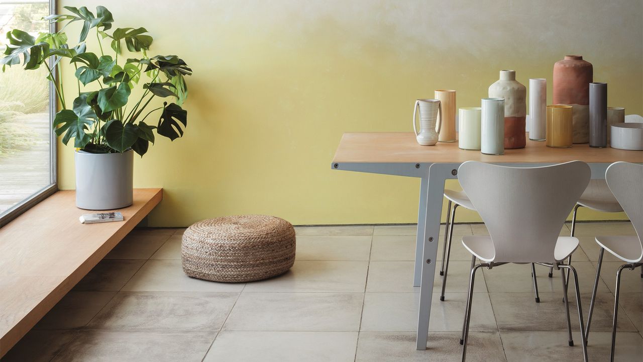 Table and white chairs in front of yellow wall