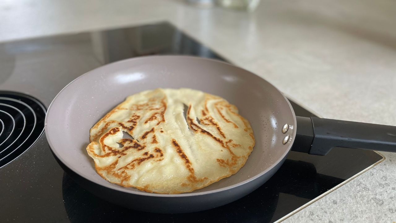 A pancake cooking in Our Place's Always Pan on an induction hob