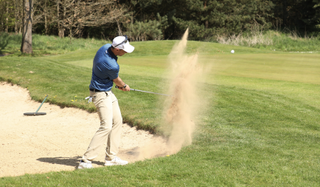 Golfer hits a greenside bunker shot