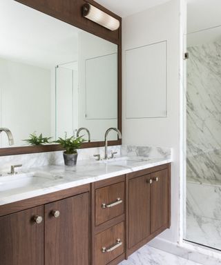 A bathroom with marble-topped wooden vanity and large mirror