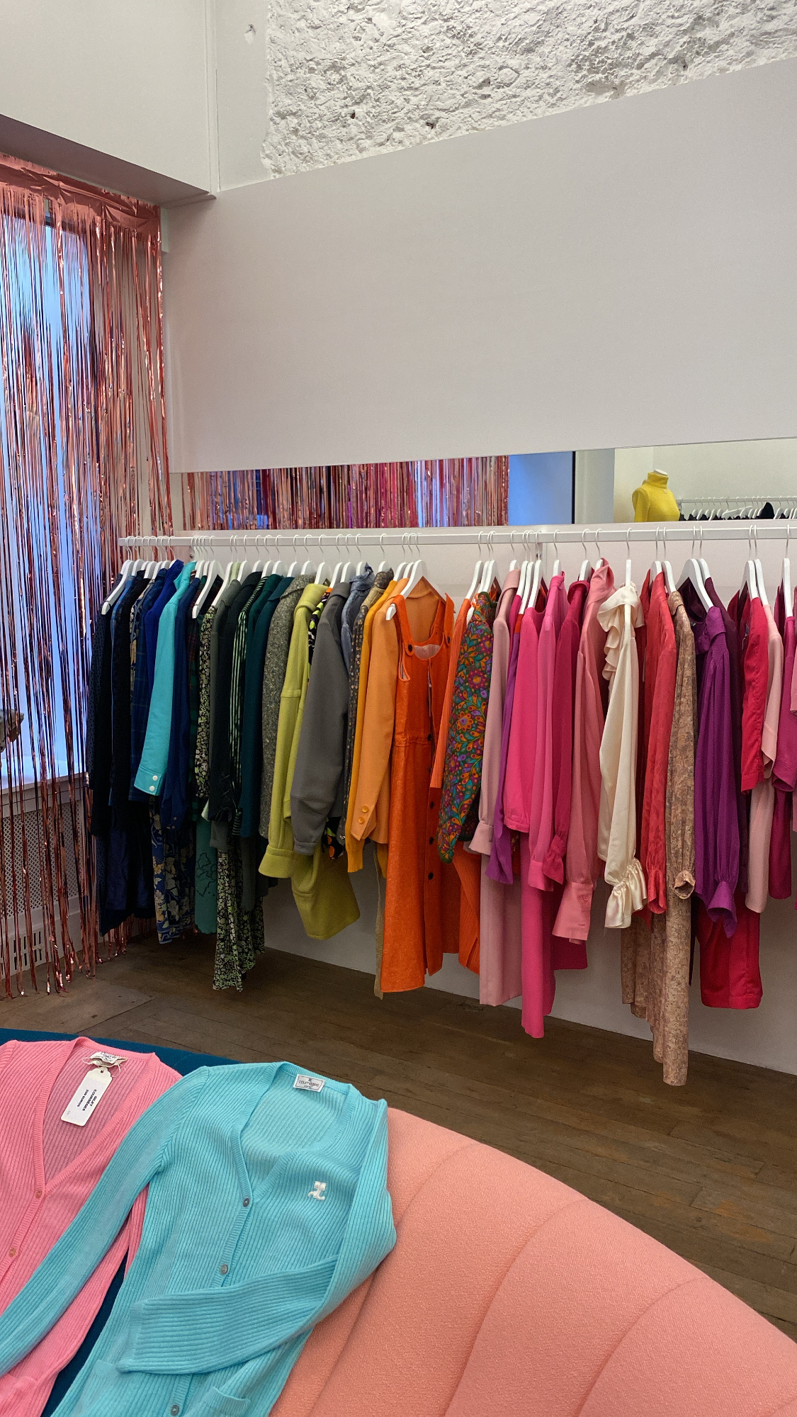 Rack of colorful clothing inside Plaisir Palace one of the best vintage stores in Paris.