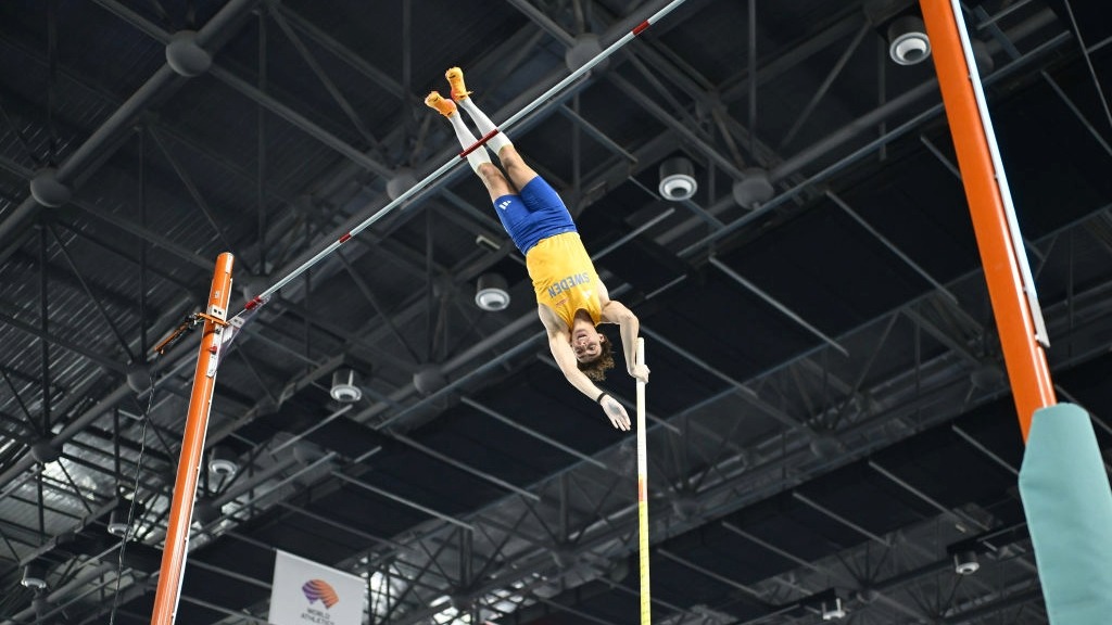 Pole vaulter Mondo Duplantis, wearing the yellow and blue colors of Sweden, soaring over the bar at the World Athletics Indoor Championships 2025 in Nanjing, China.