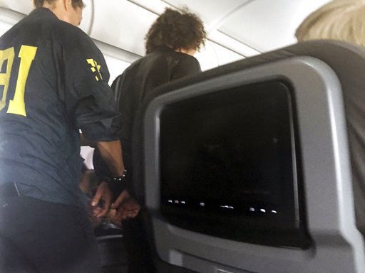 A man is escorted off an American Airlines flight after it landed in Honolulu, Friday, May 19, 2017