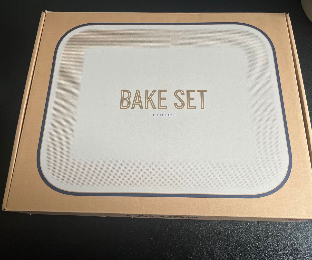 A white enamel dish with a black rim on the front of a cardboard box.