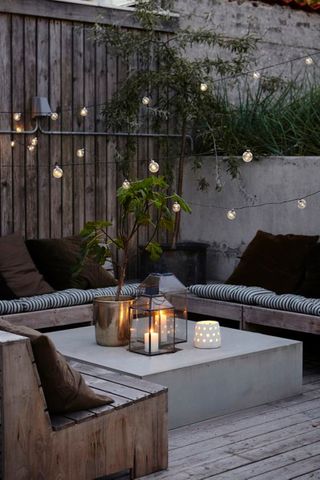 porch decor ideas Small patio with low coffee table and festoon lights