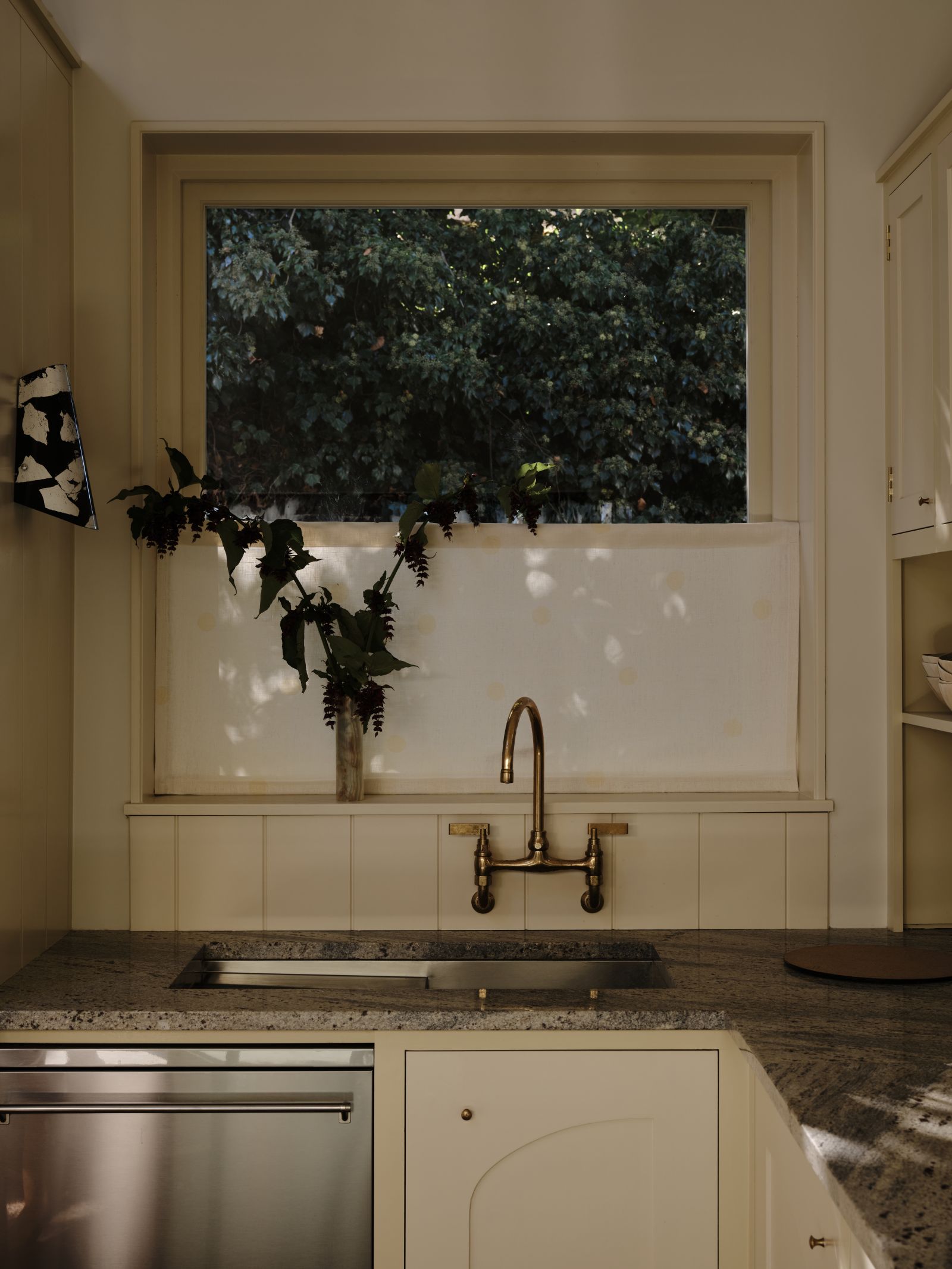 kitchen sink with a window above, cabinets are off white with a butter yellow border around them