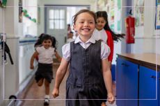 three primary school children running down a corridor excitedly at school