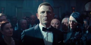 No Time To Die Daniel Craig stands in the middle of a staring crowd.