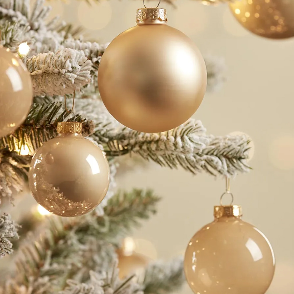 close up of a snow-covered artificial Christmas tree with matte gold baubles