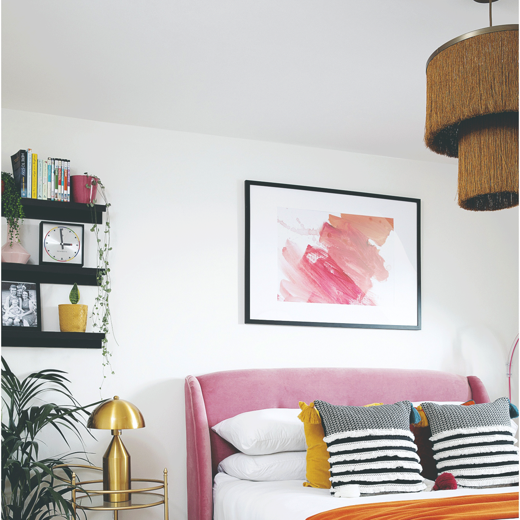 White bedroom with gold fringe lighting and pink bed