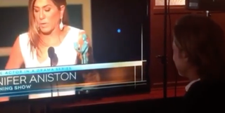 Brad Pitt watches Jennifer Aniston on a TV screen.