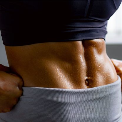 Woman in workout clothes, close up of muscled stomach after trying an In and Out ab method workout