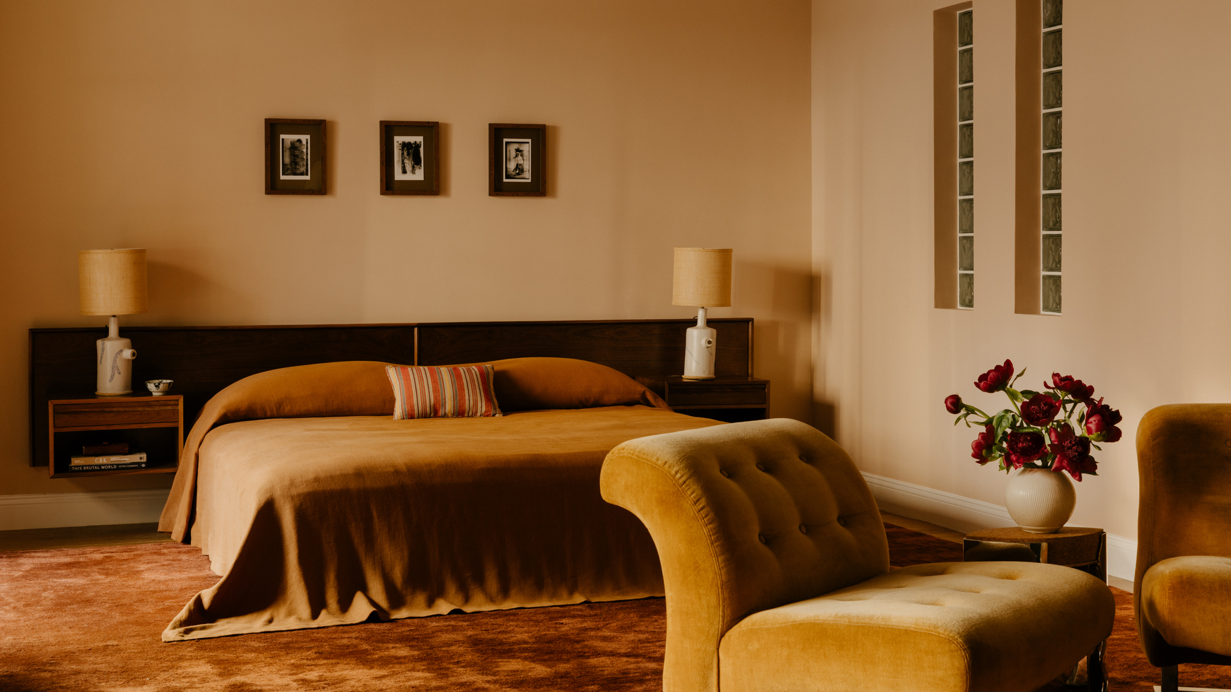 large bedroom with pale walls and mustard bedding and large dark headboard