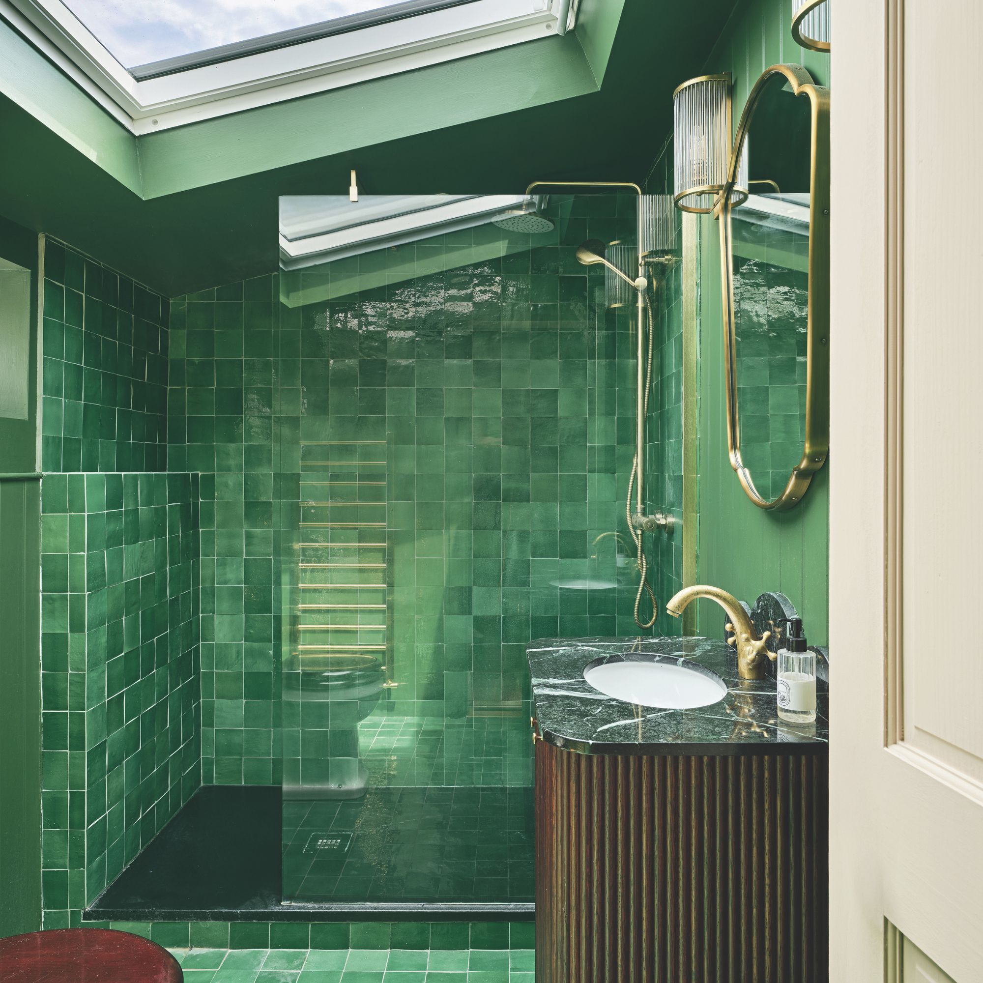 Green tile-drenched bathroom with skylight.