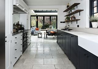 black and white cupboards in a galley kitchen leading to living room