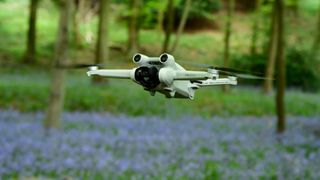DJI Mini 3 Pro drone flying in a field of bluebells