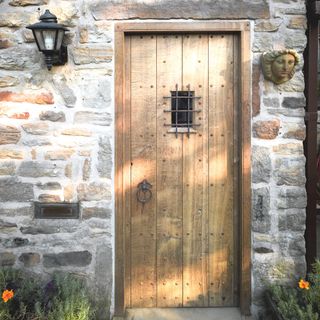 wooden tudor-style front door in stone house.