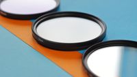 Lens filters laid on an orange and blue paper decorated table