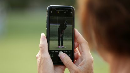 A close up of a fan filming Bubba Watson putting on their phone
