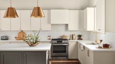 modern kitchen with white cabinets, dark gray island and copper pendant lights