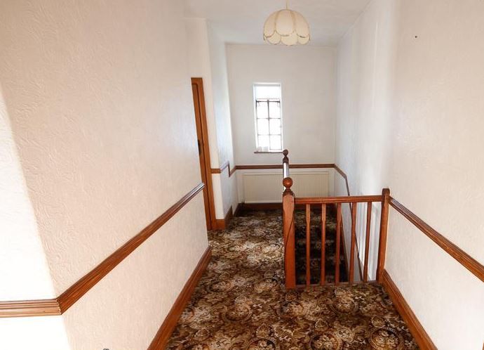 The upstairs view of the hallway with heavily patterned carpet