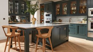 Large dark green kitchen with social kitchen island with bar stools to showcase a leading kitchen trend 2023