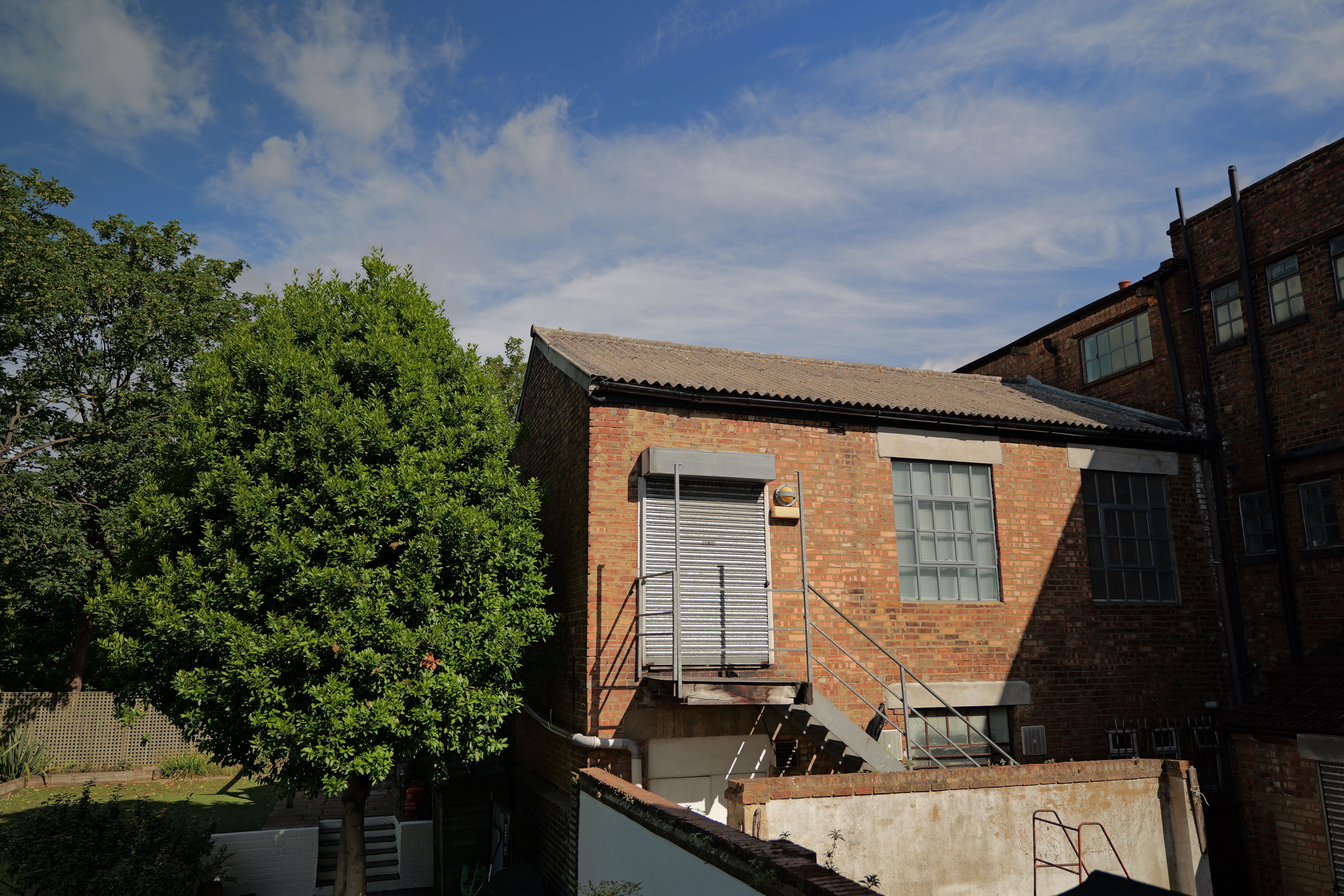 Warehouse next to a green tree in front of a bright blue sky