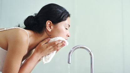 woman washing her face at the sink