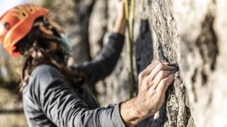 A man rock climbing wearing an orange helmet