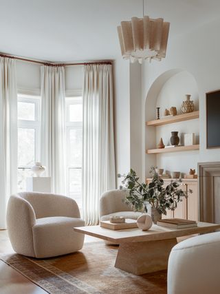 Rounded chairs and a right-angled coffee table rest on a neutral rug