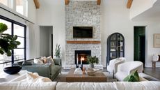 neutral living room with cream sofa and chairs and exposed brick wall with fireplace