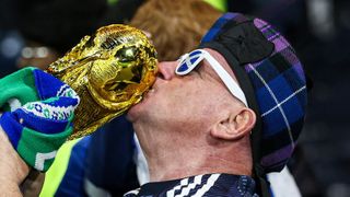 A Scotland fan kisses a replica of the Jules Rimet trophy.