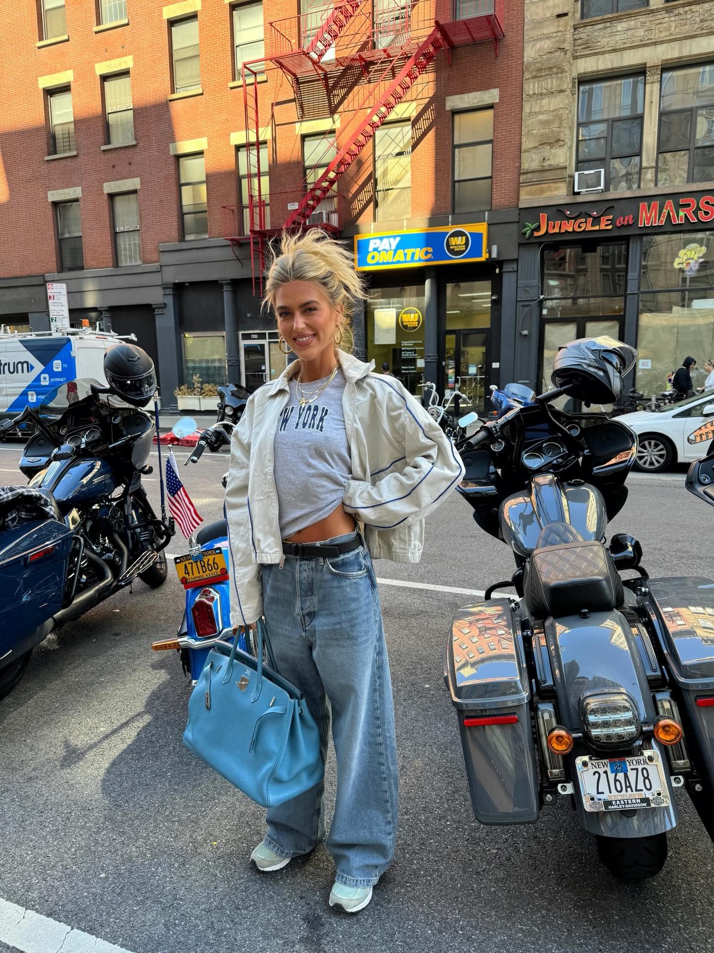 @emilisindlev wearing jeans, sneakers, graphic tee, and a sports jacket