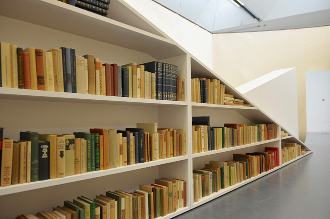 A bookshelf with three shelves and two sections. The right section has a downward diagonal top.
