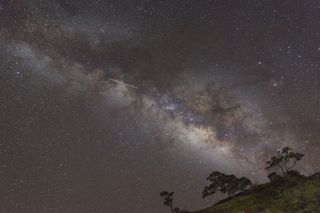 A meteor shoots across the night sky during the Southern Delta Aquariids meteor shower.