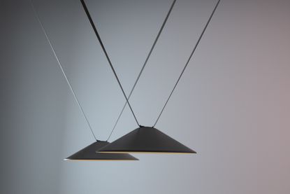 Two black triangular lamps hanging from textile ropes by Stefan Diez Vibia