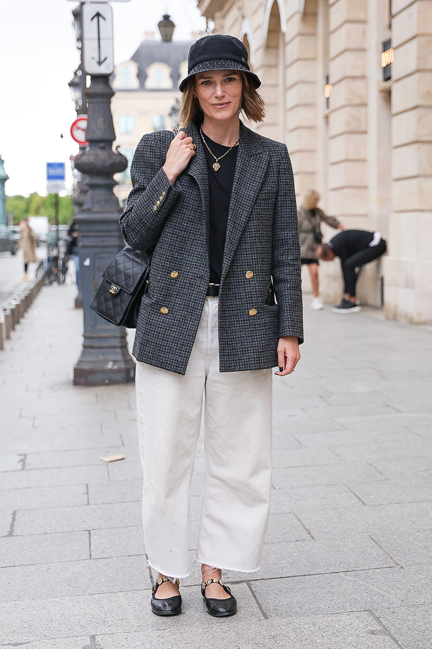 Keira Knightley wearing a bucket hat and gray coat with white pants and embellished Chanel Mary Janes in Paris