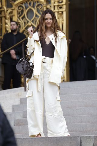 Katie Holmes walks into the zimmermann show wearing a white cargo suit with a plunge bodysuit