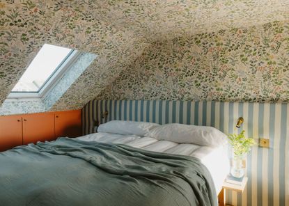 converted loft with floral wallpaper and bed with stripy headboard