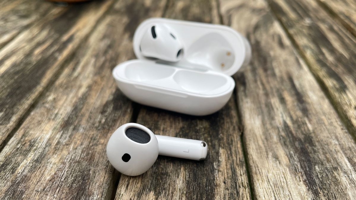 The Apple AirPods 4 with ANC &ndash; one earbud inside the case, one lying in front of it &ndash; on a wooden outside surface.