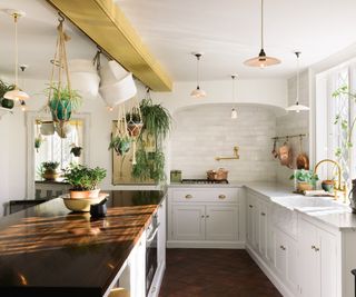 vintage white kitchen with dark wooden island countertop and dark terrcotta floors styled with vintage decor and brass hardware